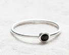 Silver ring with a black gemstone on a white fabric background