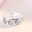 Silver ring with black cartoon character faces on a light background