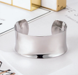 Silver bracelet on a white surface with a blurred background