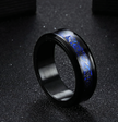 Black ring with blue engraved design on a dark background