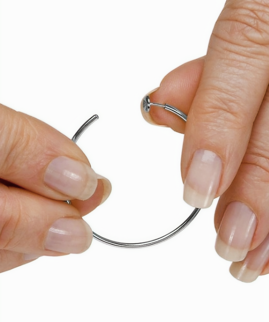 Close-up of hands holding a silver hoop earring against a white background