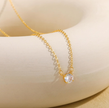 Gold necklace with a clear gemstone on a white surface