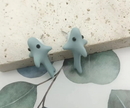 Two small blue shark figurines on a textured surface with leaves in the background