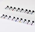 Twelve black labret-style body jewelry piercings with faceted gemstone tips in various colors, arranged in two rows on a clean white background.
