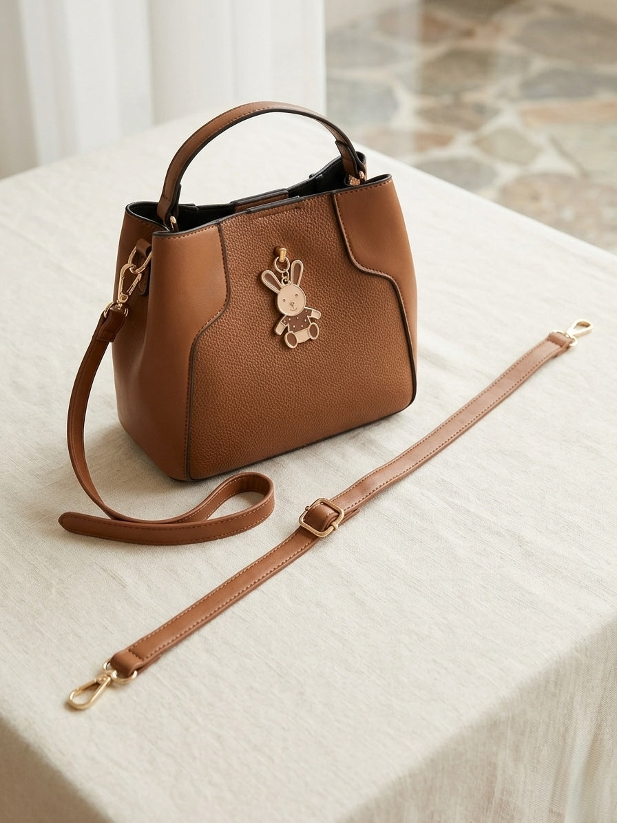 Elegant Brown Faux Leather Handbag with Decorative Charm.