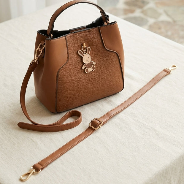 Elegant Brown Faux Leather Handbag with Decorative Charm.