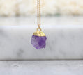 Necklace with a purple crystal pendant on a marble surface