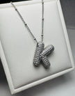 Silver necklace with a unique pendant on a textured surface