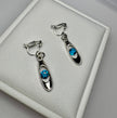 Pair of silver earrings with blue gemstones on a gray surface