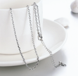 Silver chain necklace on a white plate with a white background